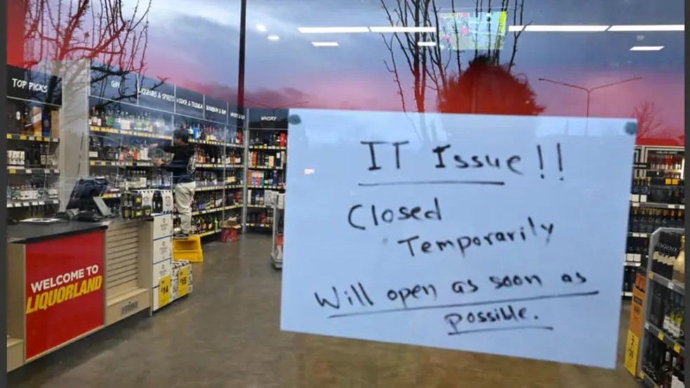 Uma placa na frente de uma loja alerta sobre fechamento temporário devido a problemas de tecnologia em Canberra, Austrália — Foto: Reuters (via BBC)