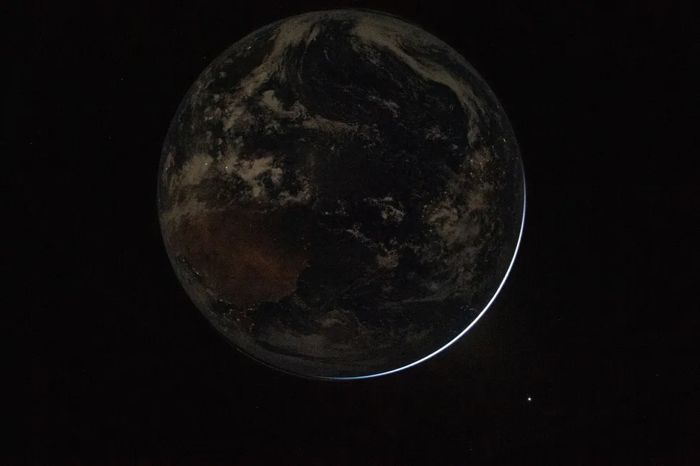 Mais uma imagem da Terra praticamente no escuro, com apenas um filete de luz — Foto: Divulgação/NASA