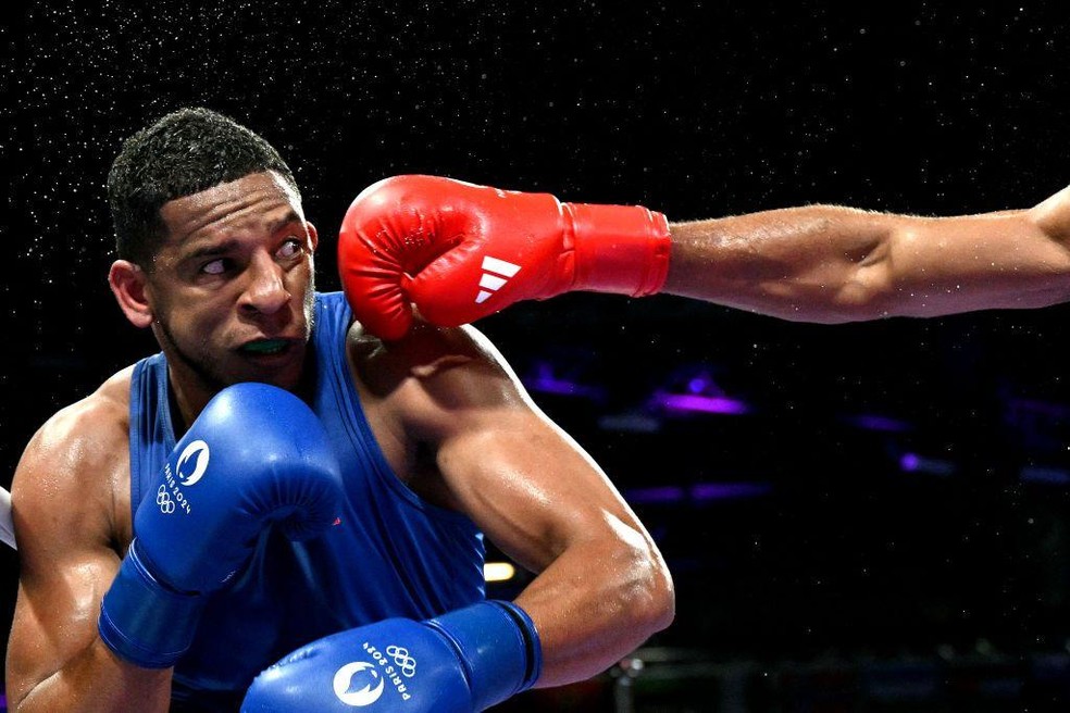 Fonte BBC News — Foto: O espanhol Enmanuel Reyes Pla recebe um soco do rival, o belga Victor Schelstraete, em uma luta de boxe