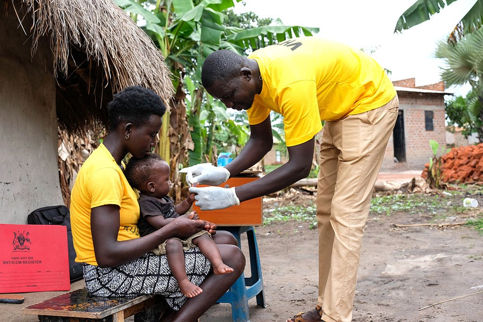 Denish Odule, oficial de saúde do distrito de Apac, na Uganda, coleta uma amostra de sangue de bebê para fazer um diagnóstico rápido da malária, em abril de 2025 — Foto: Hajarah Nalwadda/Getty Images