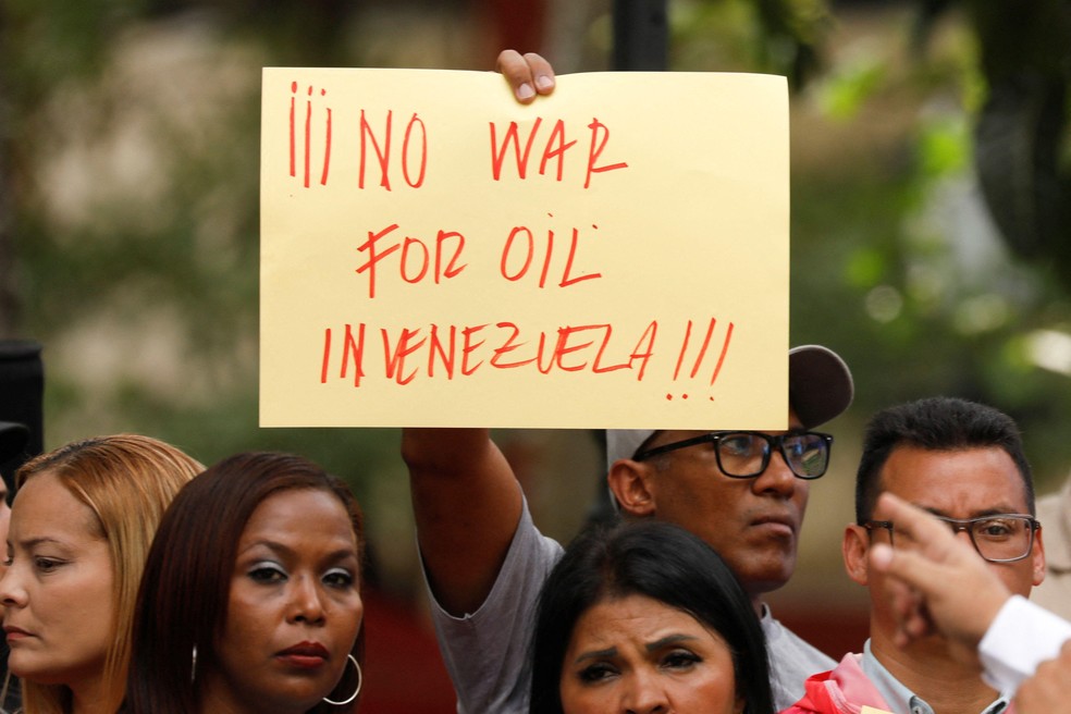 Homem segura cartaz com a placa "Não à guerra por petróleo na Venezuela" — Foto: BBC News fonte