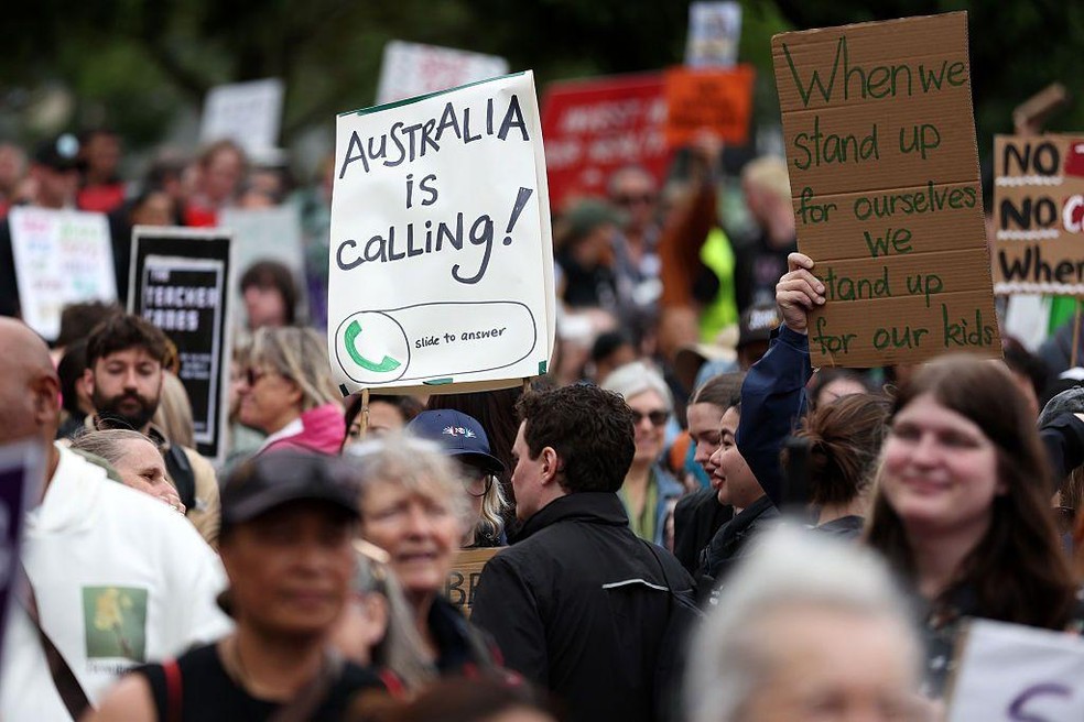 Com o lema 'A Austrália nos chama', trabalhadores dos setores de educação e saúde alertam o governo da Nova Zelândia de que os baixos salários os empurram à emigração — Foto: BBC News fonte